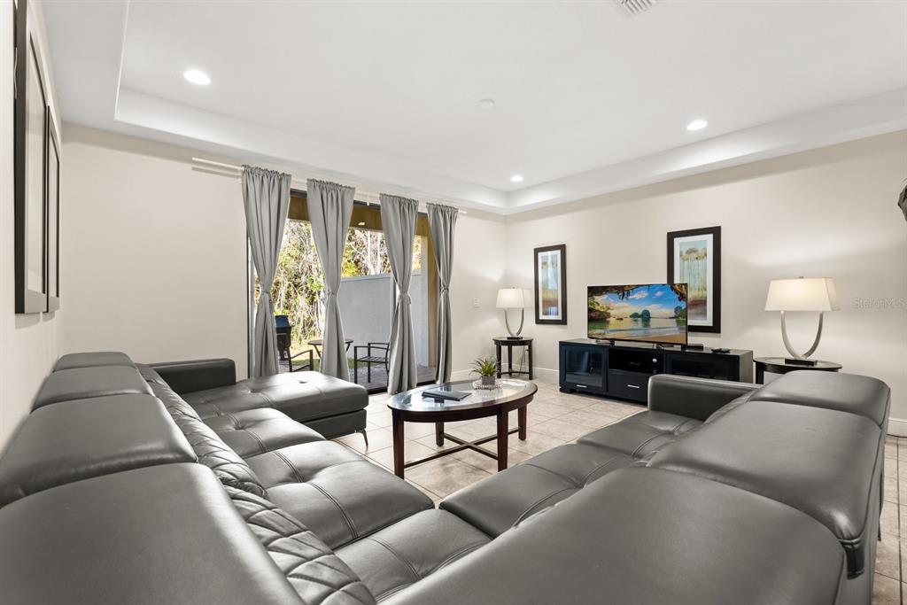 A living room features a large grey sectional sofa, tile flooring, and sliding glass doors — 8193 ROSEVILLE BOULEVARD, DAVENPORT, FL