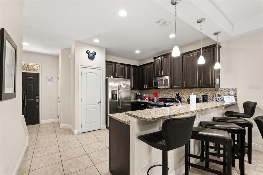 A kitchen features dark wood cabinets, granite countertops, a breakfast bar, and stainless steel appliances — 8193 ROSEVILLE BOULEVARD, DAVENPORT, FL