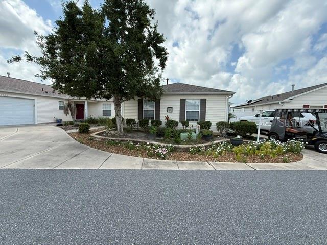 A single-story house with a large tree, a concrete driveway, and a parked golf cart — 7618 SE 171ST SUN VALLEY PLACE, THE VILLAGES, FL