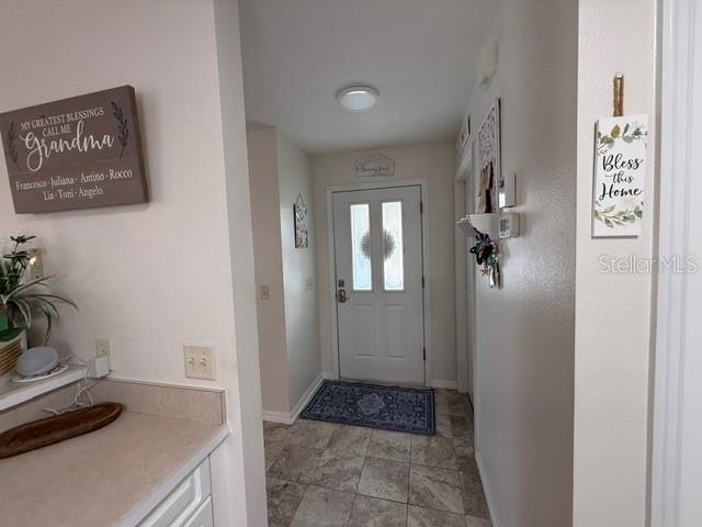 An entryway features a white front door, tiled flooring, and decorative wall signs — 7618 SE 171ST SUN VALLEY PLACE, THE VILLAGES, FL