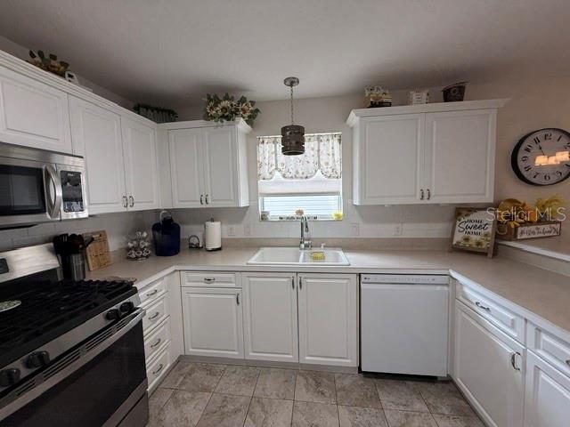 A kitchen features white cabinets, stainless steel appliances, a double sink, and tile flooring — 7618 SE 171ST SUN VALLEY PLACE, THE VILLAGES, FL