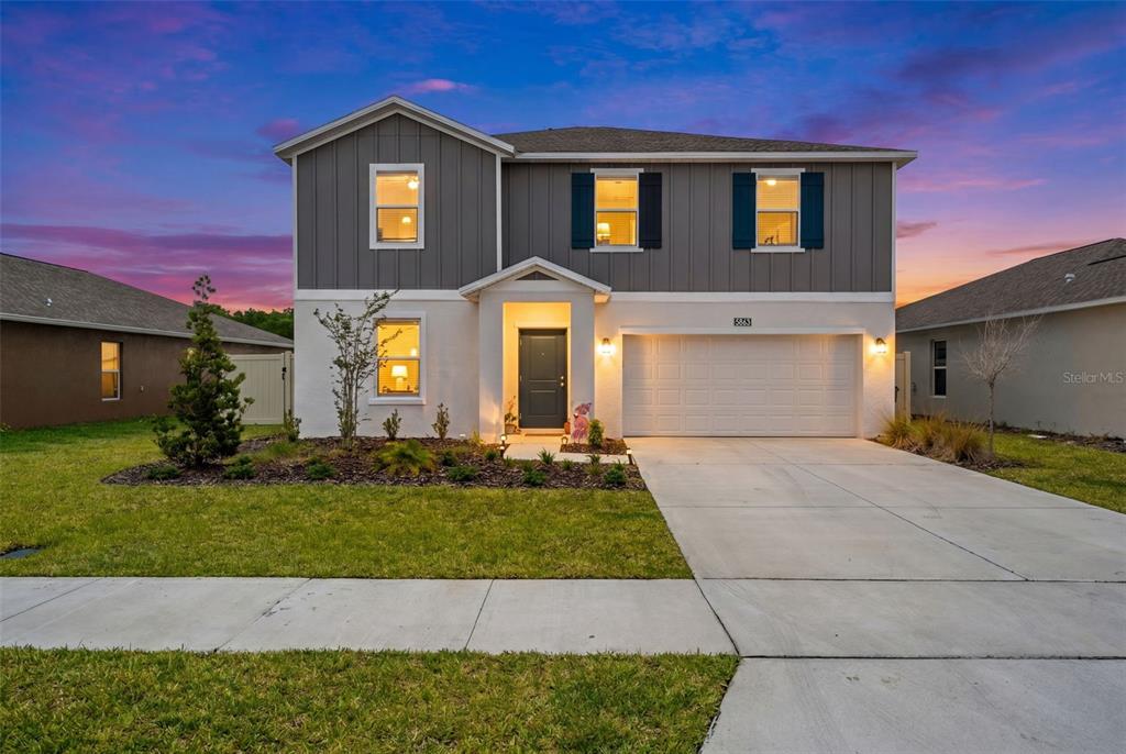A two-story house with a white stucco lower level, gray vertical siding, and a garage — 5863 LE MARIN WAY, KISSIMMEE, FL