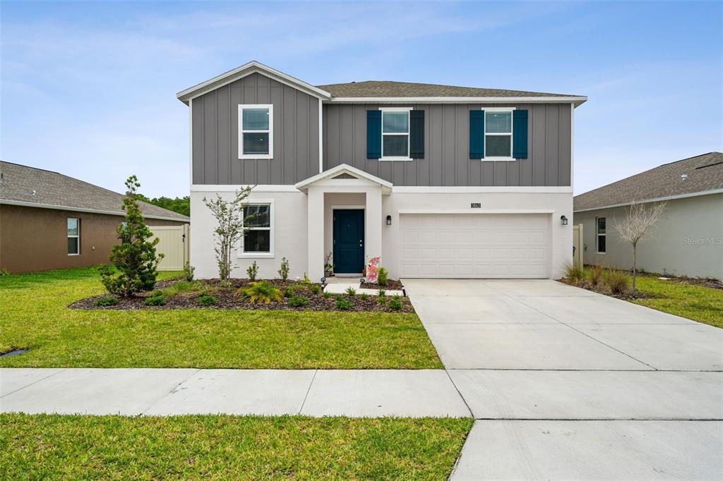 A two-story house with gray vertical siding, a white stucco lower level, and a garage — 5863 LE MARIN WAY, KISSIMMEE, FL