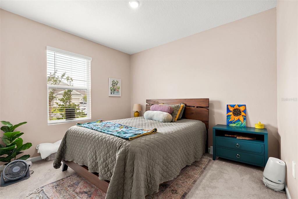 A bedroom features a bed with a wooden headboard, a blue nightstand, and a window — 5863 LE MARIN WAY, KISSIMMEE, FL