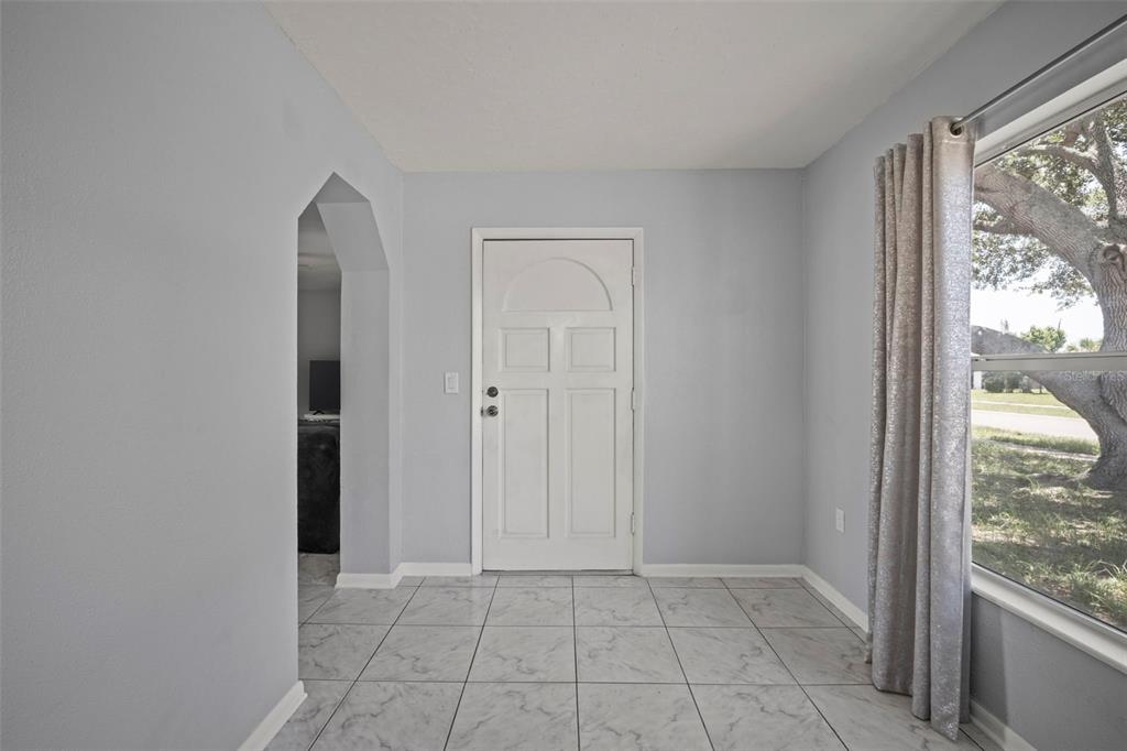 An entryway with light gray walls, white tile flooring, and a white front door — 1010 ILLINOIS ROAD, COCOA, FL
