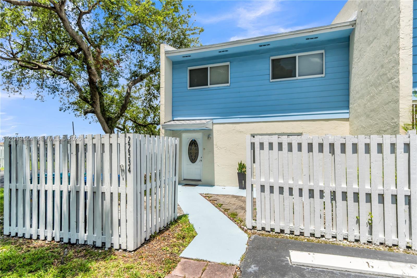 A two-story townhouse exterior features blue horizontal siding, a white front door, and a picket fence — 22334 SW 103rd Ct, Cutler Bay FL 33190, CUTLER BAY, FL