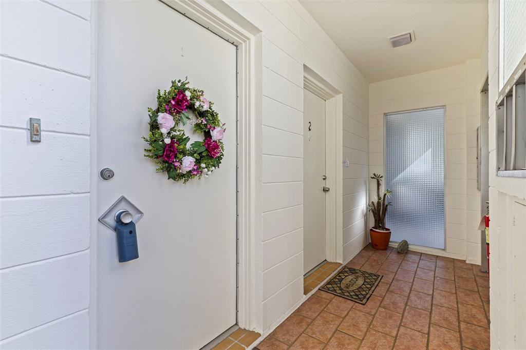 A tiled entryway features two white doors, a floral wreath, and a potted plant — 1036 NORTH SHORE DRIVE NE UNIT 1, ST PETERSBURG, FL