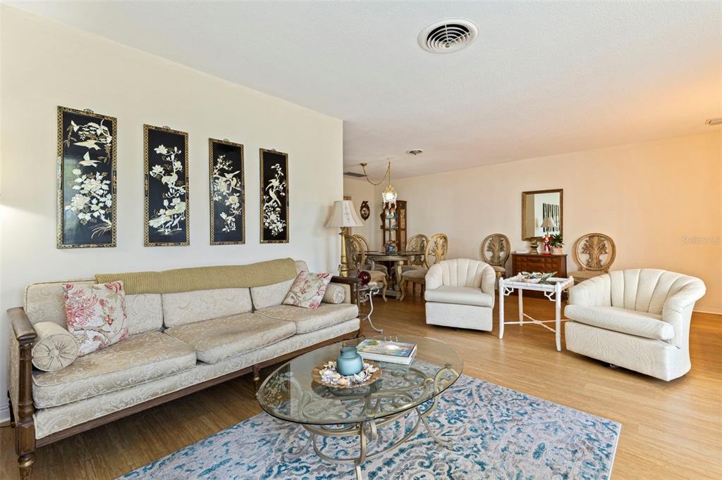 A living room features a beige sofa, two white armchairs, and four wall-mounted decorative panels — 1036 NORTH SHORE DRIVE NE UNIT 1, ST PETERSBURG, FL