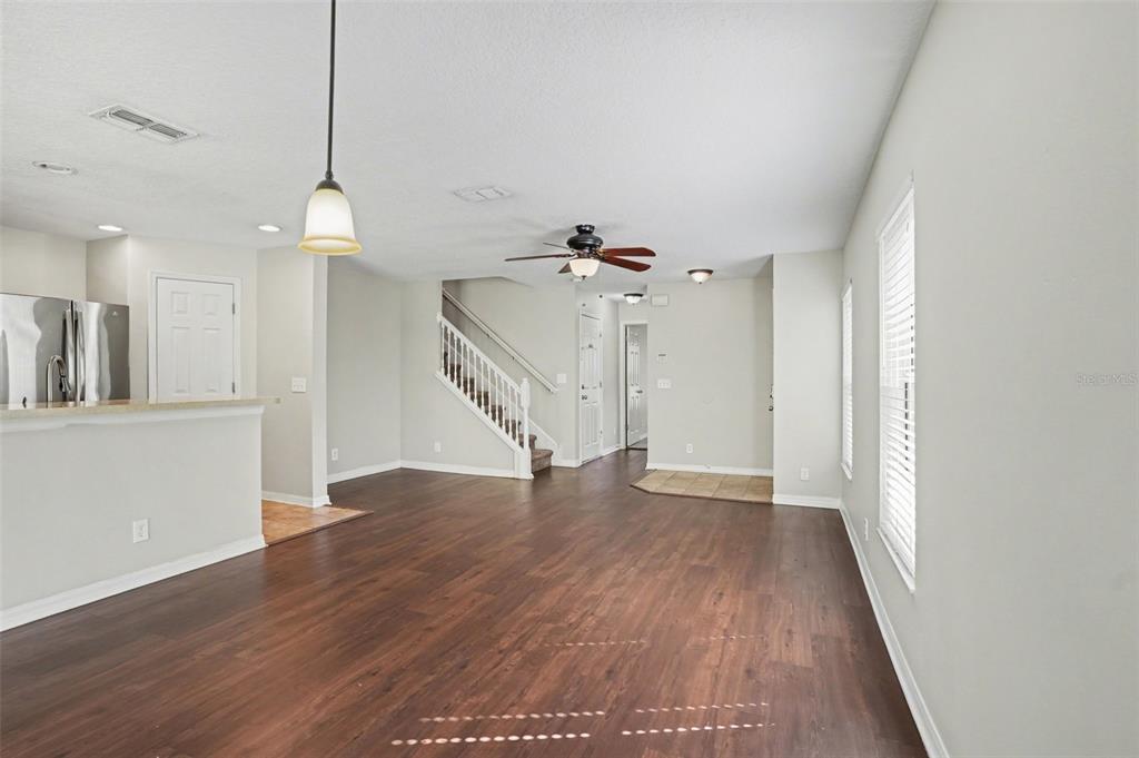 An open-concept living area features dark wood-look flooring, a staircase, and a kitchen island — 3128 ROYAL TUSCAN LANE, VALRICO, FL
