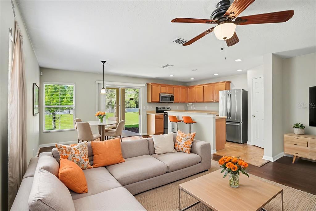 An open-concept living room and kitchen featuring a sectional sofa, dining area, and wood cabinetry — 3128 ROYAL TUSCAN LANE, VALRICO, FL
