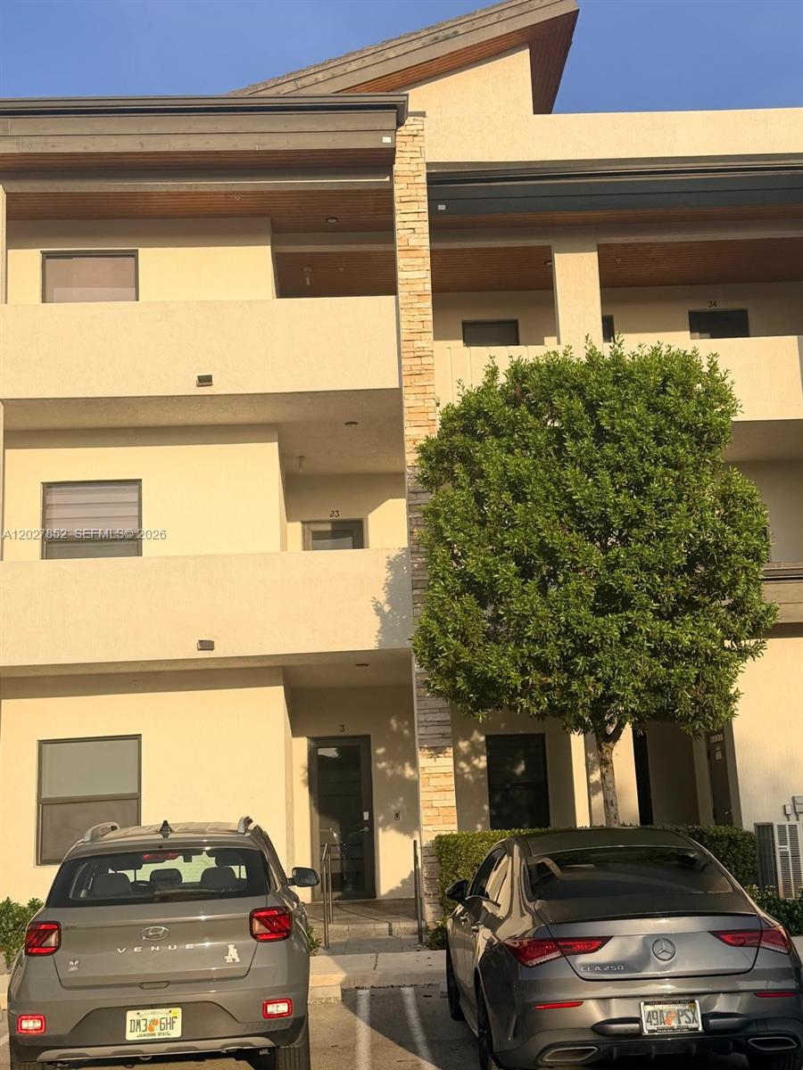 A three-story apartment building exterior features beige stucco walls, stone accents, and two parked cars — 8005 NW 104th Ave # 3, Doral FL 33178, DORAL, FL