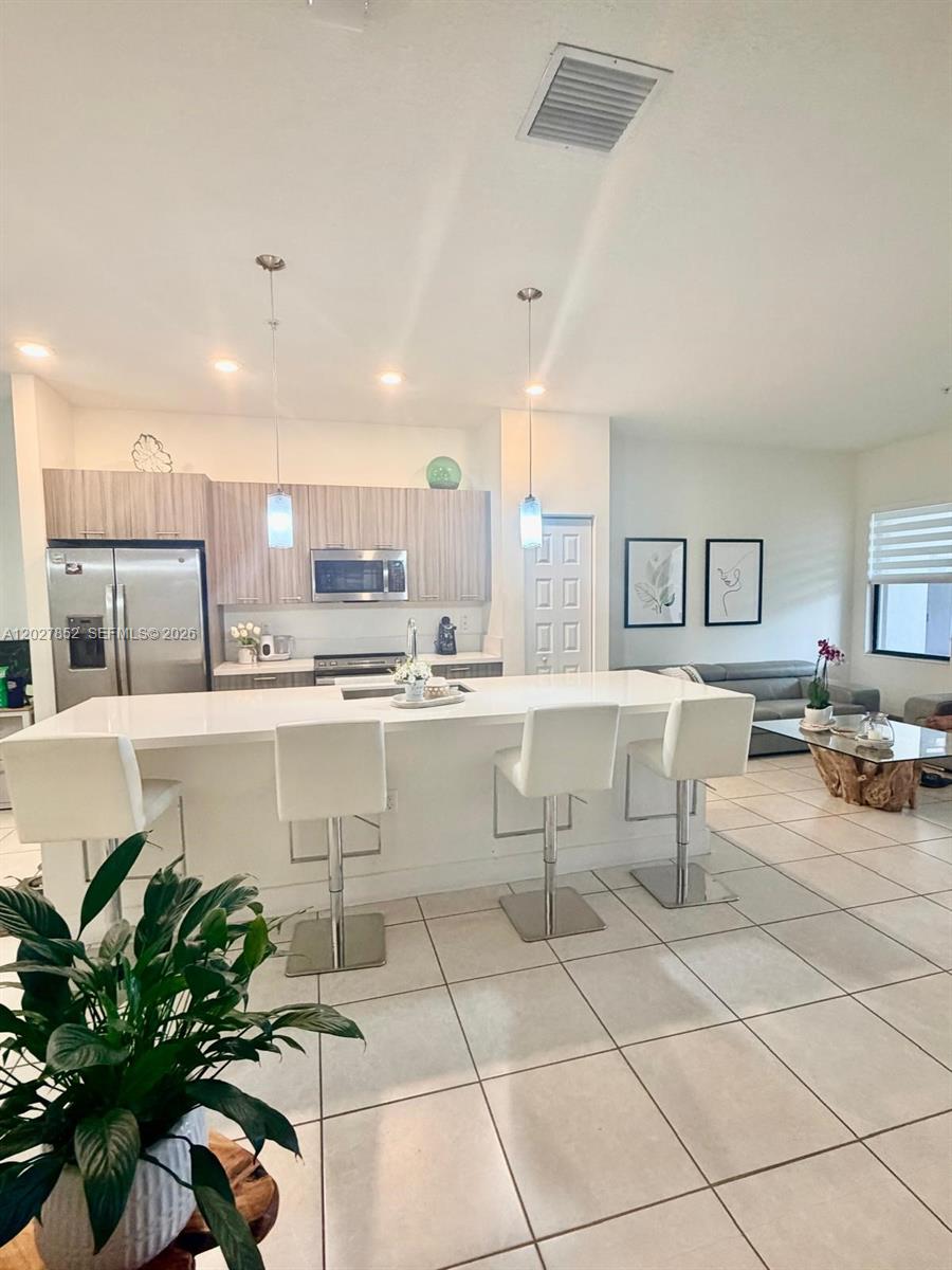 A modern kitchen features a large white island with bar stools and light wood cabinetry — 8005 NW 104th Ave # 3, Doral FL 33178, DORAL, FL