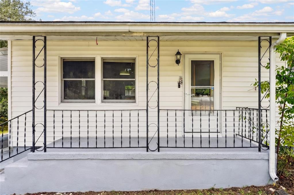 A front porch with a concrete floor, black metal railings, and white horizontal siding — 16220 SE 83RD COURT, SUMMERFIELD, FL