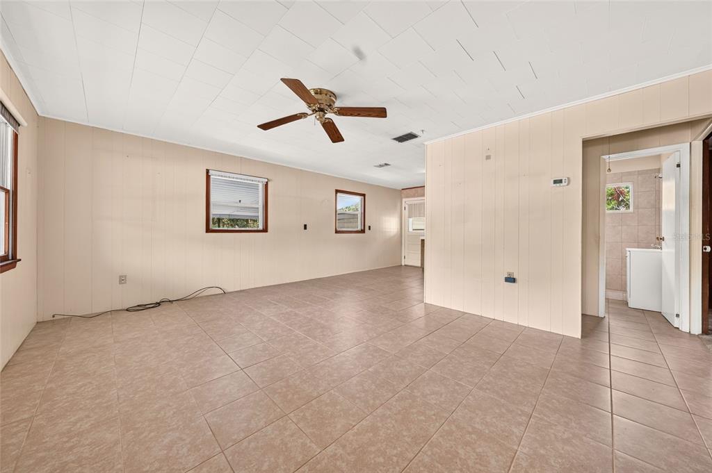 An empty room with beige paneled walls, tiled floors, a ceiling fan, and a doorway — 16220 SE 83RD COURT, SUMMERFIELD, FL