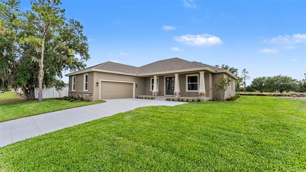 A single-story house with a tan exterior, stone accents, and a two-car garage — 535 SHANKLIN AVENUE, BARTOW, FL