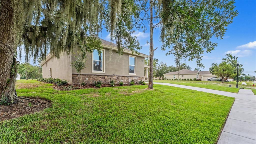 A side view of a tan house with stone veneer siding and Spanish moss trees — 535 SHANKLIN AVENUE, BARTOW, FL
