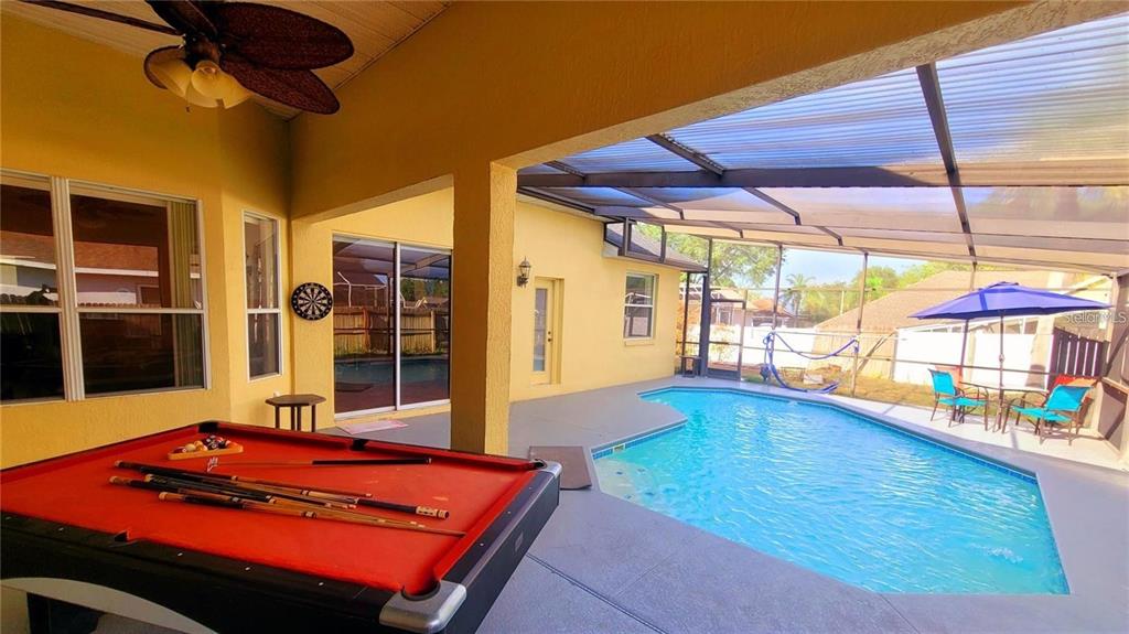 A covered patio features a red pool table, a swimming pool, and a screened enclosure — 10 NEVADA LOOP ROAD, DAVENPORT, FL