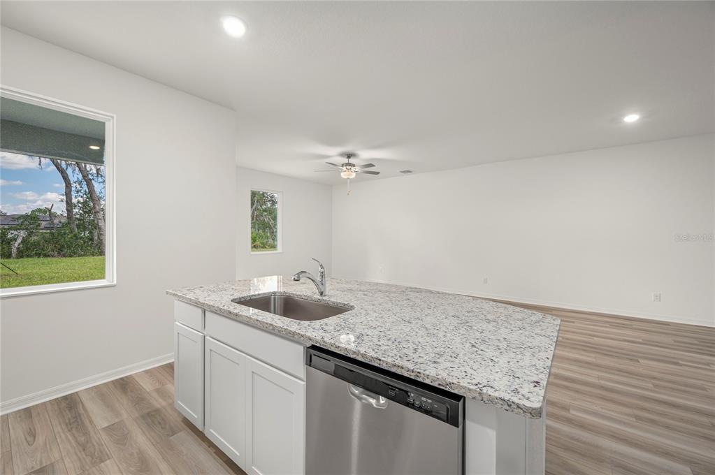 A kitchen island with a stainless steel sink and dishwasher sits in a white room — 306 BOWFIN COURT, POINCIANA, FL