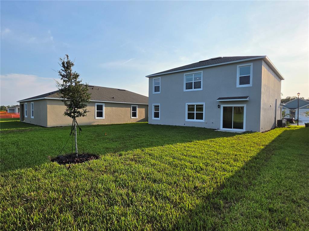 The exterior view shows a two-story house and a single-story house with grassy yards — 1013 CHAMPION RIDGE DRIVE, DAYTONA BEACH, FL