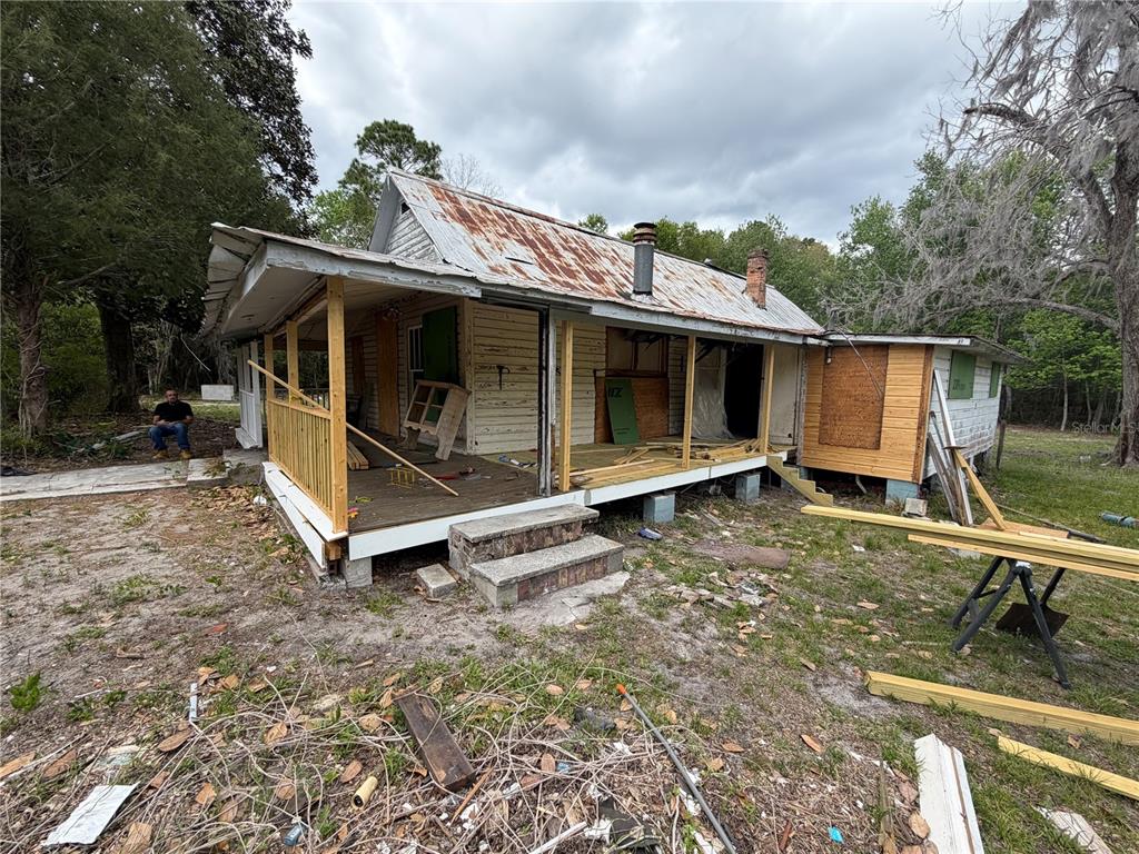 A weathered house with a metal roof and an unfinished wooden porch under construction — 10033 SW COUNTY ROAD 225, STARKE, FL