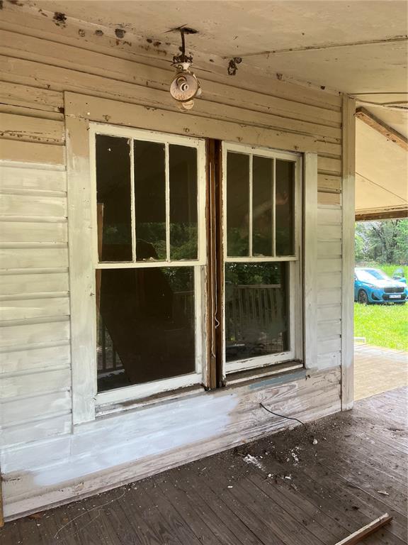 A porch with weathered wood siding, a double window, and an exposed light fixture — 10033 SW COUNTY ROAD 225, STARKE, FL