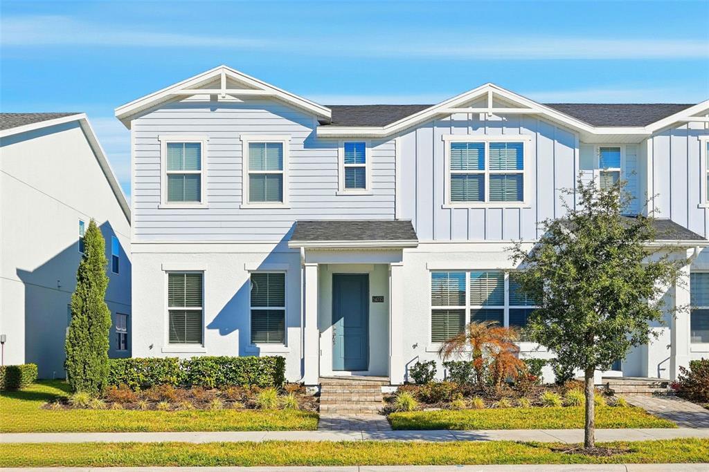 A two-story townhouse with white stucco and light blue siding under a blue sky — 14075 LOCHEND WAY, WINTER GARDEN, FL