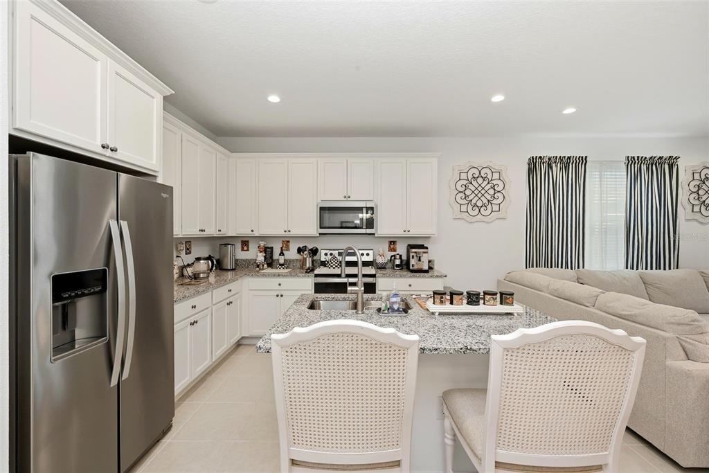 A kitchen with white cabinets, granite countertops, and an island with two chairs — 14075 LOCHEND WAY, WINTER GARDEN, FL