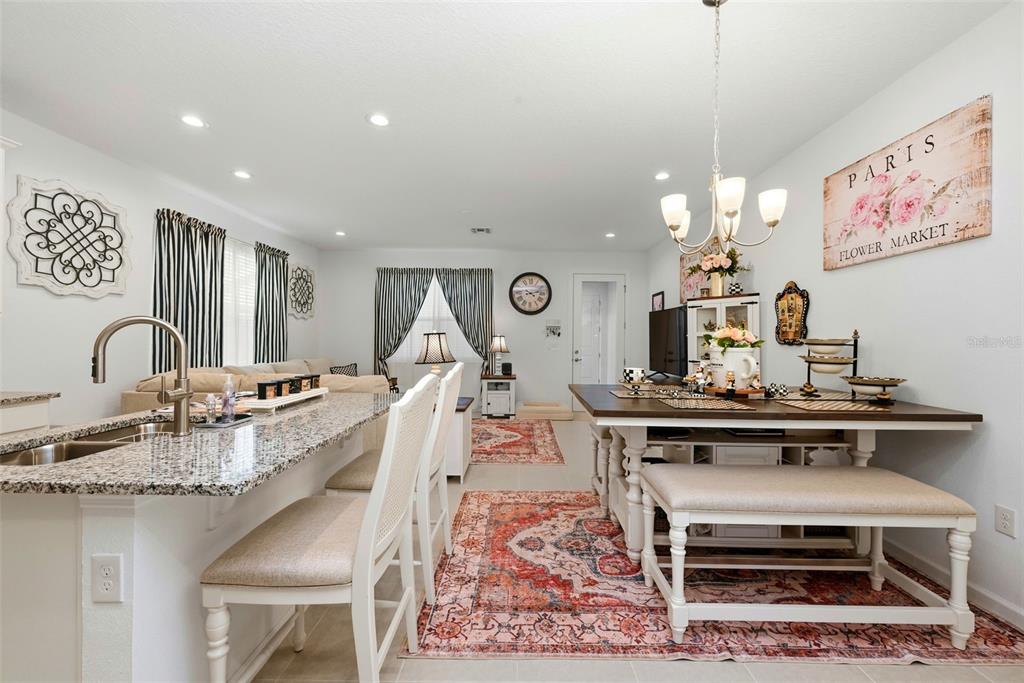 A living room and kitchen area with white cabinetry, a television console, and area rugs — 14075 LOCHEND WAY, WINTER GARDEN, FL