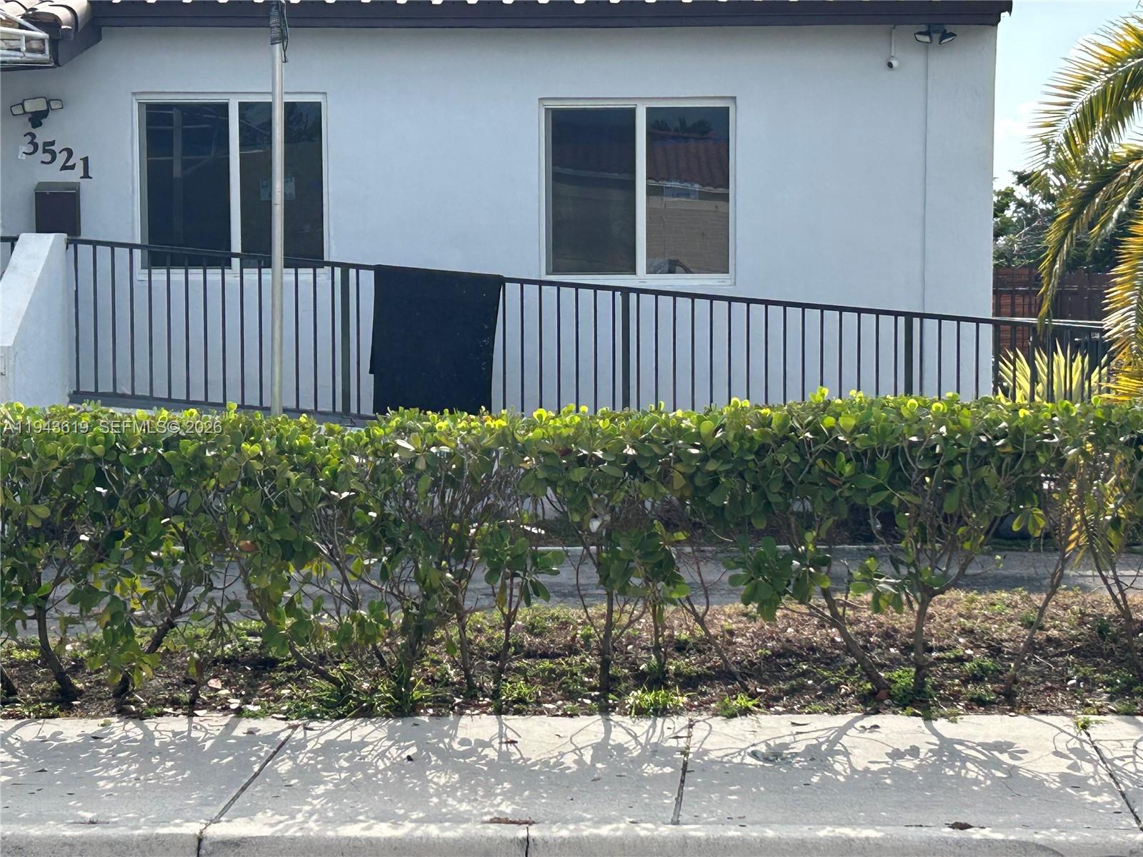 The exterior of a white building features a metal ramp with railings and a hedge — 3521 E 4th Ave, Hialeah FL 33013, HIALEAH, FL