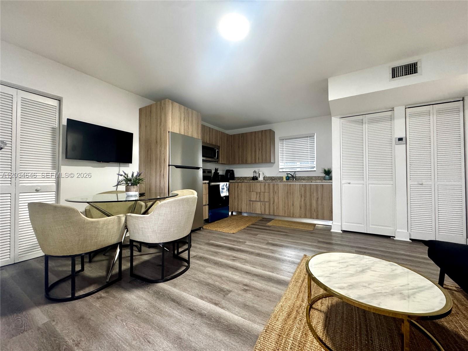 This open-concept kitchen and dining area features light wood cabinetry, stainless steel appliances, and flooring — 1684 SW 10th St, Miami FL 33135, MIAMI, FL