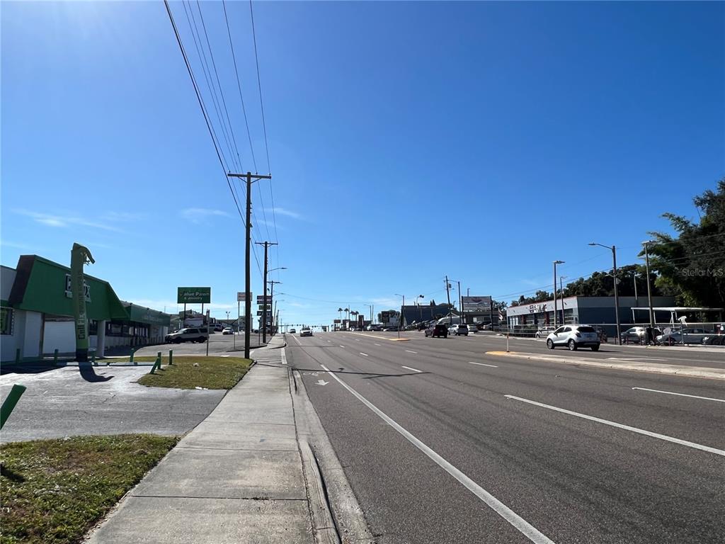 A view of a multi-lane road with a sidewalk and commercial buildings under a clear sky — 8610 N SUWANEE AVENUE, TAMPA, FL