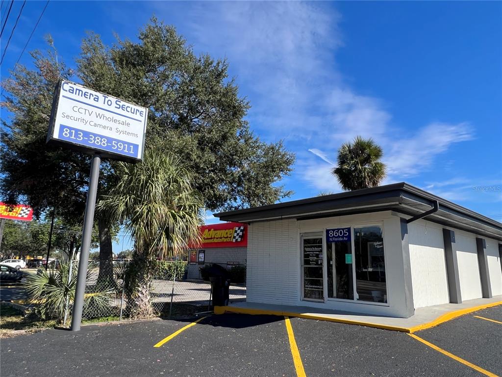 A commercial building with a white exterior and a sign for a security camera business — 8610 N SUWANEE AVENUE, TAMPA, FL