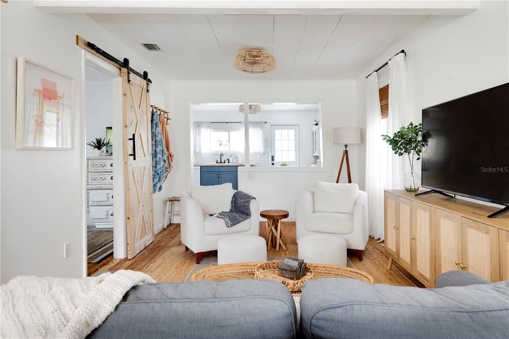 A living room features white armchairs, a sliding barn door, and a television on a cabinet — 315 HOPE STREET, TARPON SPRINGS, FL