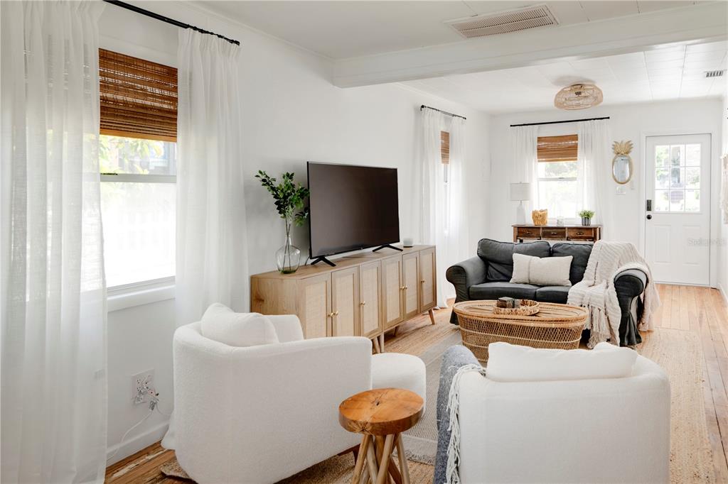 A bright living room features white walls, wood flooring, a television console, and two white armchairs — 315 HOPE STREET, TARPON SPRINGS, FL