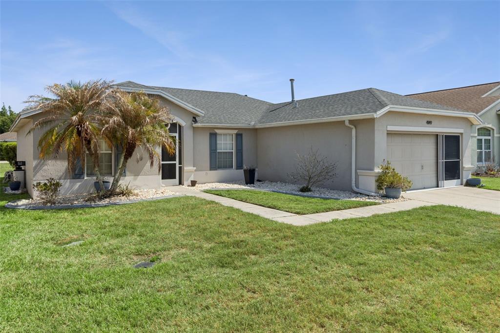 A single-story house with a beige stucco exterior, a gray shingled roof, and a garage — 4149 WINDCHIME LANE, LAKELAND, FL