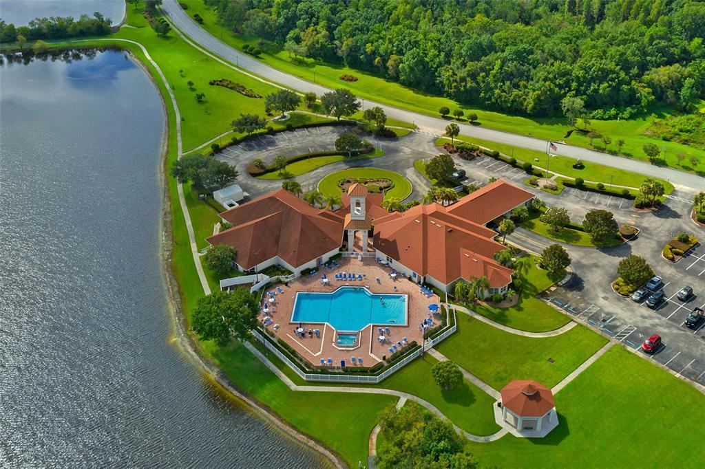 An aerial view shows a community clubhouse with a swimming pool, parking lot, and lake — 4149 WINDCHIME LANE, LAKELAND, FL