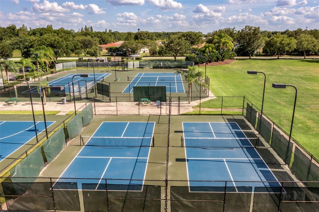 An aerial view shows four outdoor tennis courts surrounded by chain-link fencing and green space — 4149 WINDCHIME LANE, LAKELAND, FL