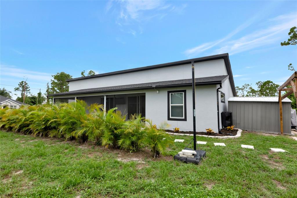 A white house with a screened-in patio and landscaping sits on a grassy lawn — 1458 E HALLMARK BOULEVARD, NORTH PORT, FL