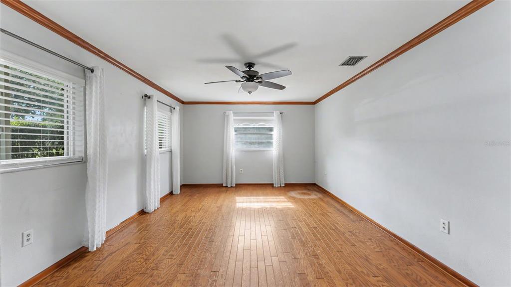 An empty room with hardwood floors, white walls, crown molding, and a ceiling fan — 1145 E GEORGE STREET, BARTOW, FL