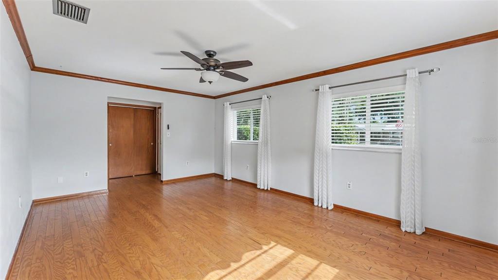 An empty room with light wood flooring, white walls, a ceiling fan, and two windows — 1145 E GEORGE STREET, BARTOW, FL