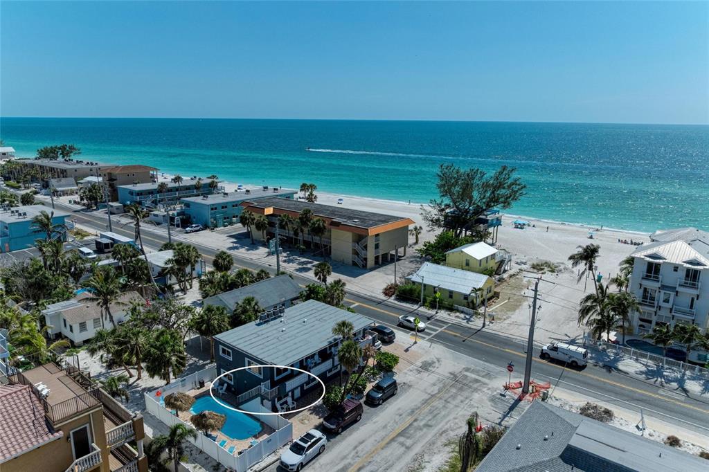 An aerial view shows a multi-story building with a swimming pool and patio area — 101 25TH STREET N UNIT 1, BRADENTON BEACH, FL