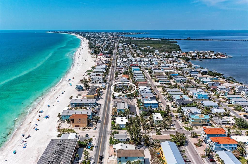 An aerial view shows a coastal town with a beach, ocean, and a circled property — 101 25TH STREET N UNIT 1, BRADENTON BEACH, FL
