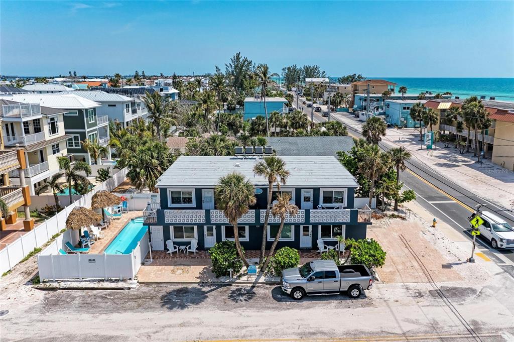 An aerial view of a two-story blue building with a pool and a parked truck — 101 25TH STREET N UNIT 1, BRADENTON BEACH, FL