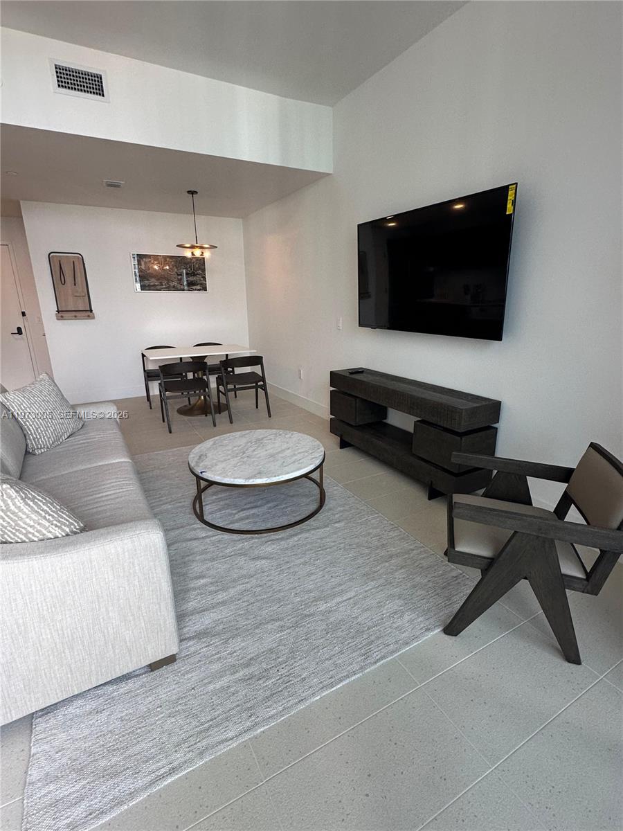 A living room features a sofa, a round marble coffee table, and a wall-mounted television — 159 NE 6th St # 4811, Miami FL 33132, MIAMI, FL