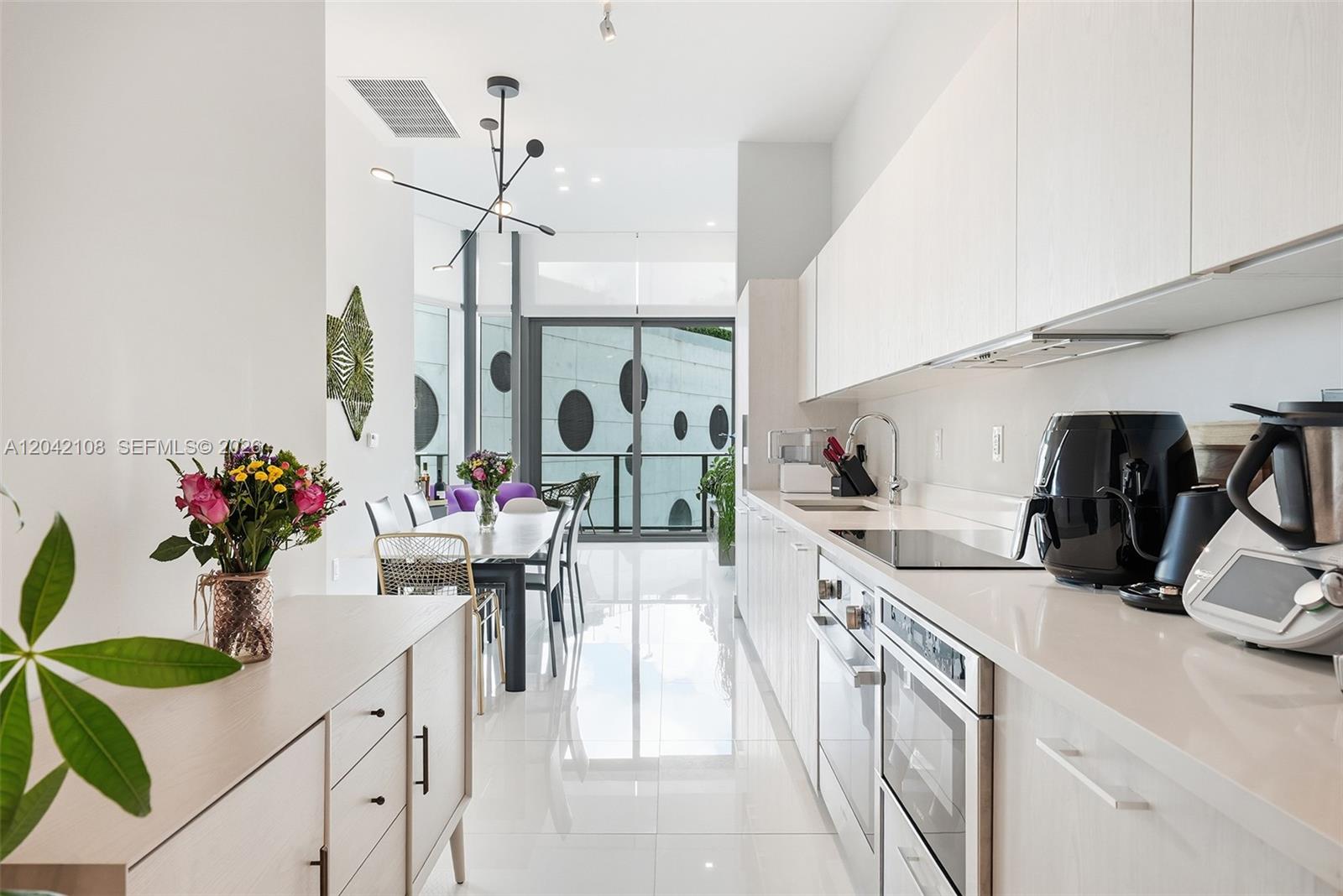 A modern white kitchen features sleek cabinetry, stainless steel appliances, and an adjacent dining area — 501 NE 31st St # 401, Miami FL 33137, MIAMI, FL