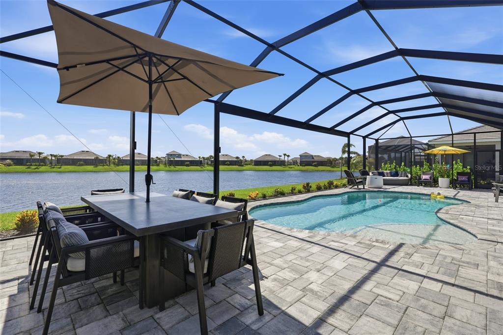 A screened-in patio features a dining set, a swimming pool, and a view of water — 15357 RIVER BIRCH COURT, PUNTA GORDA, FL