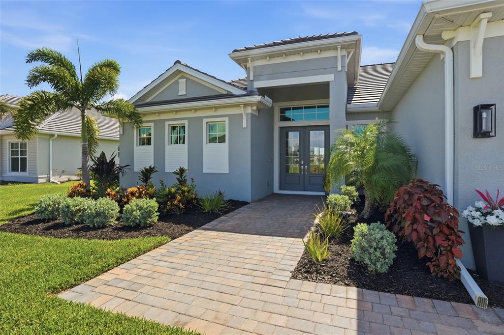 A gray single-story house features a paver walkway leading to a double-door entryway — 15357 RIVER BIRCH COURT, PUNTA GORDA, FL