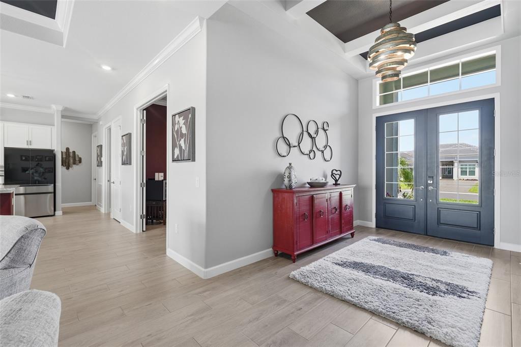 A bright entryway features light wood-look tile flooring, a red console table, and double front doors — 15357 RIVER BIRCH COURT, PUNTA GORDA, FL