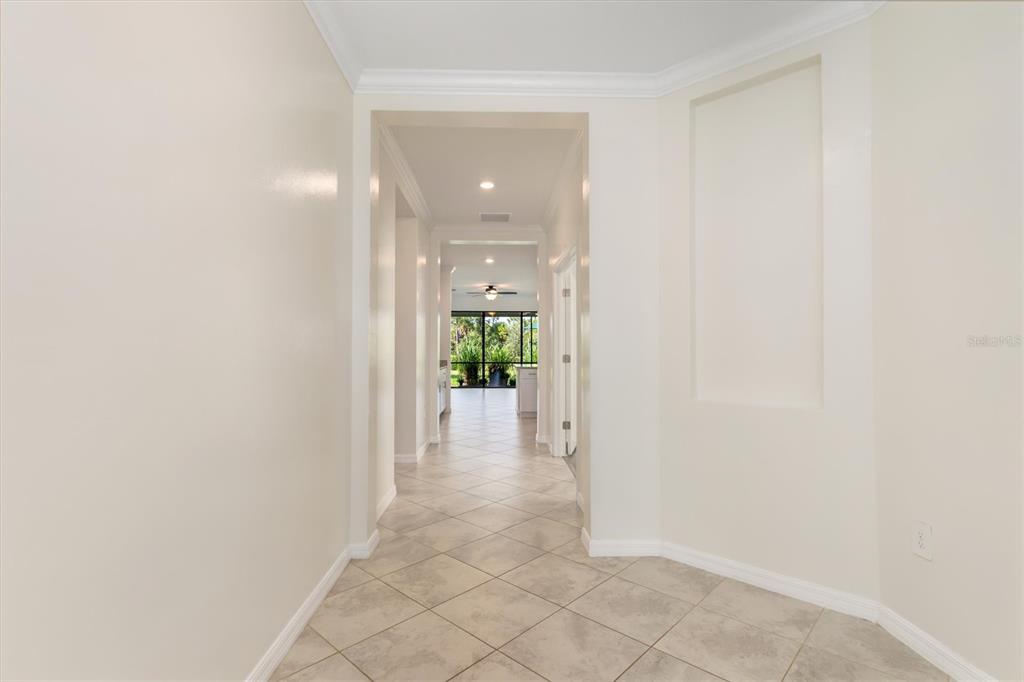 A tiled hallway leads from an entryway toward a bright room with a ceiling fan — 11125 BALFOUR STREET, VENICE, FL