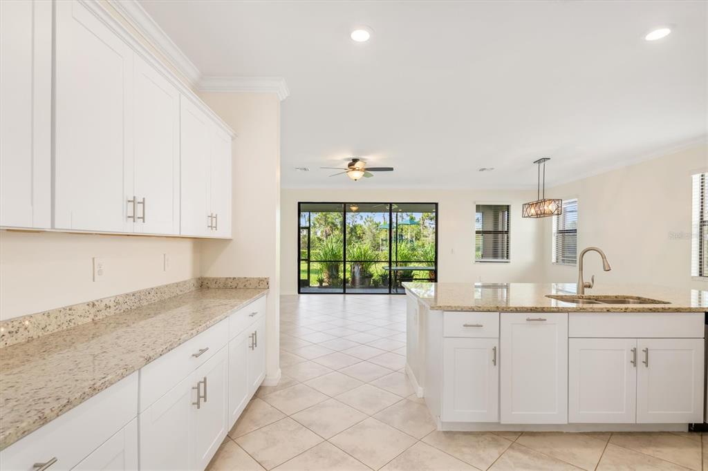 A kitchen with white cabinets, granite countertops, and an island overlooking a screened-in patio — 11125 BALFOUR STREET, VENICE, FL